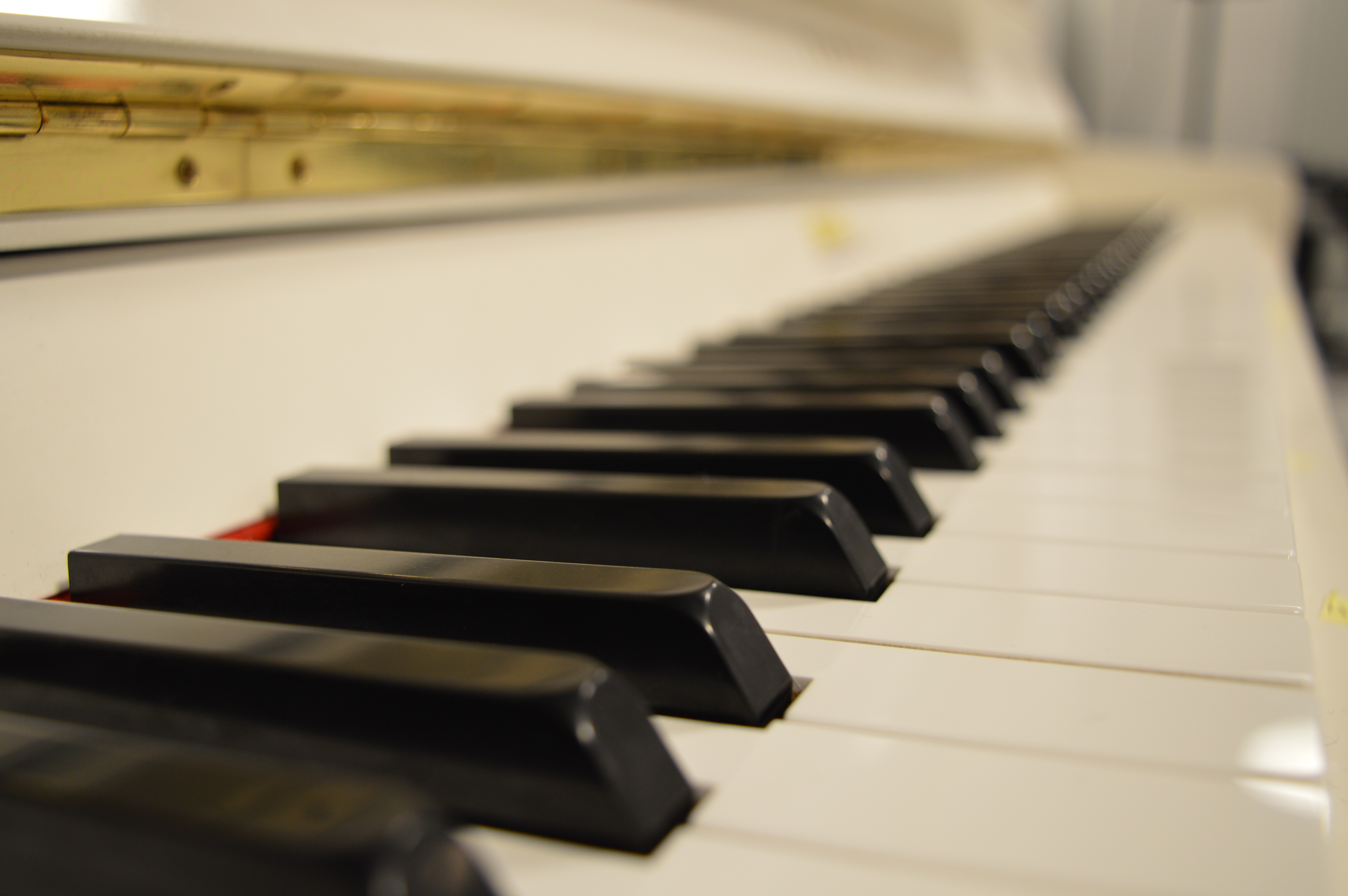 ett vitt piano, inzomat på tangenterna. 