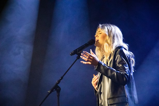 Ung kvinna sjunger i mikrofon